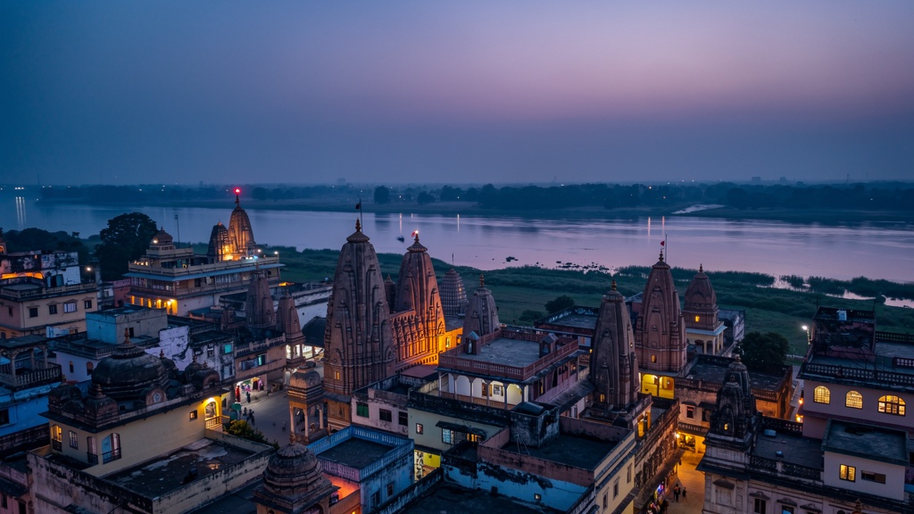 Vrindavan's temple spires at blue hour, warm lights beginning to glow