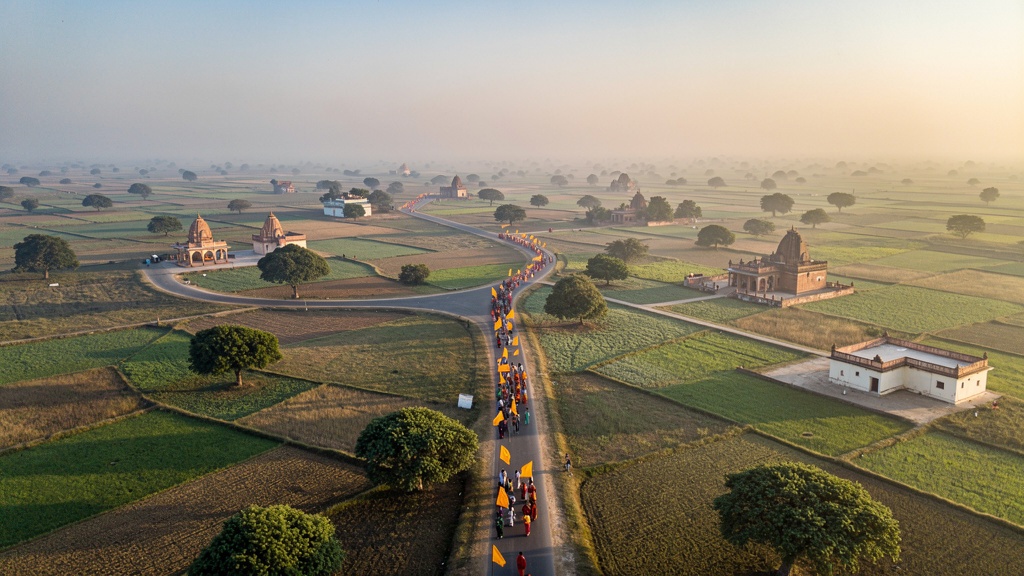 A yatra procession with saffron flags crossing the Braj countryside at dawn
